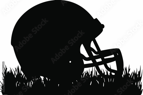 Silhouette of a football helmet nestled in grass side view.