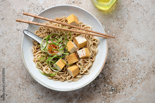 Ramen with smoked tofu, marinated egg and spring onion on a beige granite background, horizontal shot, flat lay
