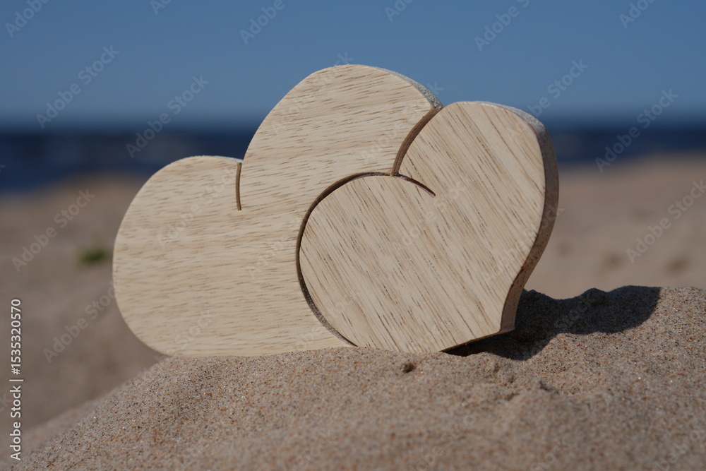 Two Wooden Interlocking Hearts on a Sandy Dune with Distant Lake Two Wooden Interlocking Hearts on a Sandy Dune with Distant Lake