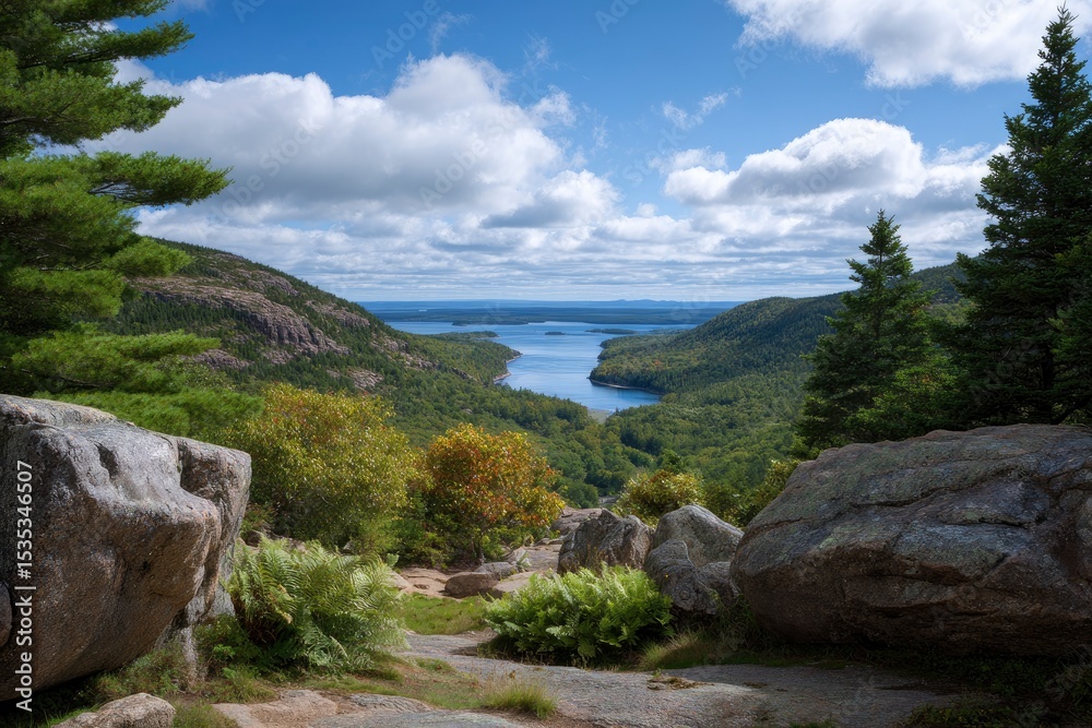 Fototapeta premium A scenic vista showcases a winding lake between wooded hills rocks in the foreground under a partly cloudy sky