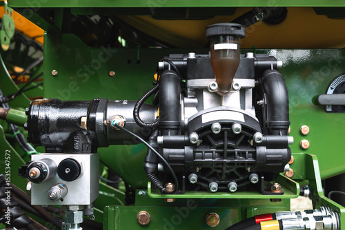 Diaphragm pump used in agricultural machinery, with hydraulic connections, transparent upper filter and pipes.