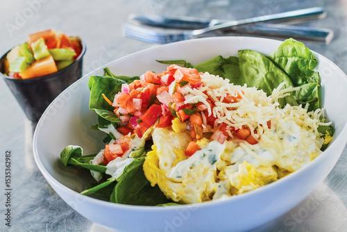 breakfast bowl with raw spinach, shredded cheese, pico de gallo, and topped with a fried egg
