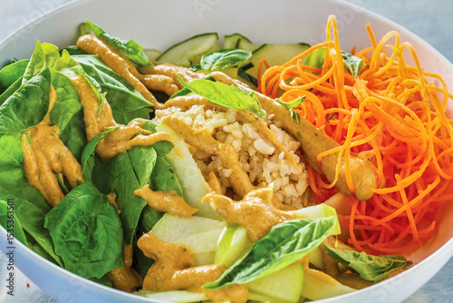 mixed green salad topped with brown rice, carrot, cucumber, and apple