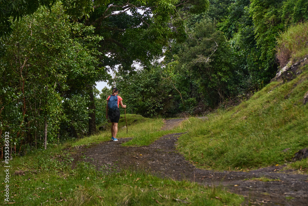 Fototapeta premium Beautiful European woman hiking in La Vallée de Ferney, Mauritius. Outdoor adventure in lush tropical forest with scenic mountain views. Active lifestyle and nature exploration.