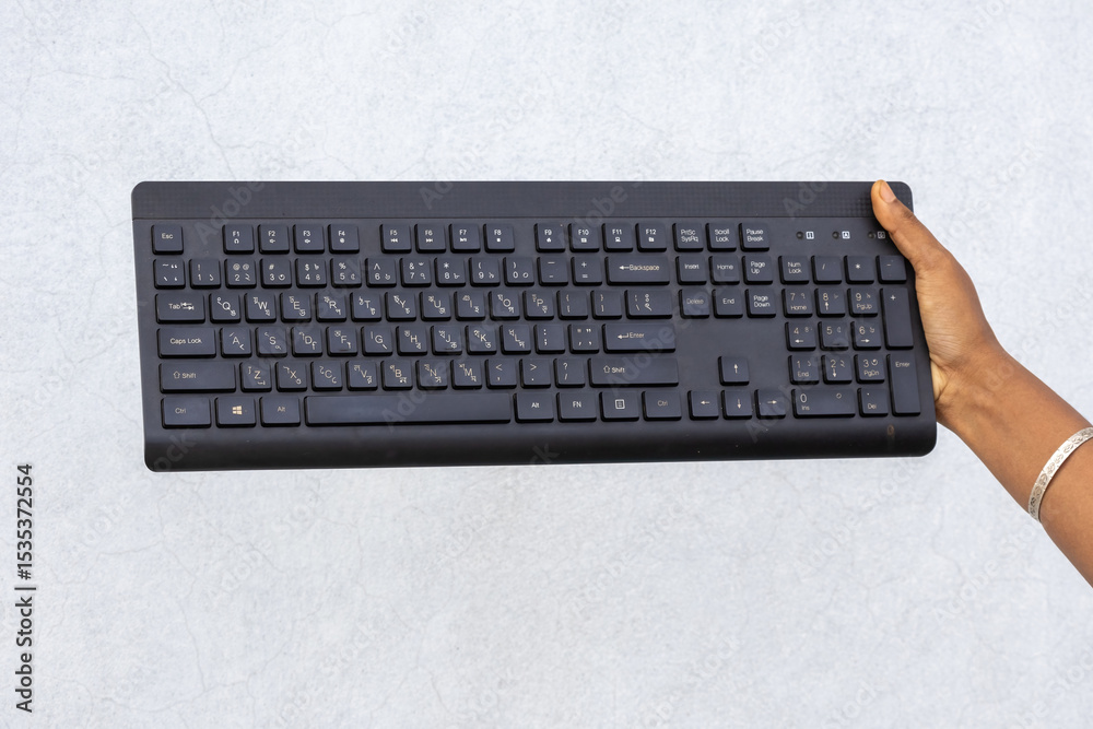 Female hand holding black keyboard with Bengali language layout on white wall background. Modern technology, communication, education. Female hand holding black keyboard with Bengali language layout on white wall background. Modern technology, communication, education.