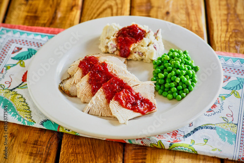 sliced turkey breast, mashed potatoes, and steamed peas with a spicy cranberry gravy