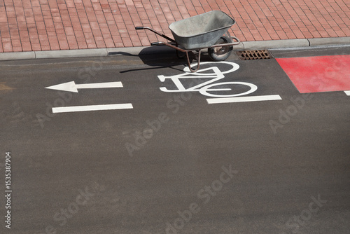 leere Schubkarre auf Fahrradspur einer asphaltierten Strasse
