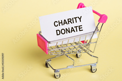 Small Shopping Cart With Charity Donate Sign on Yellow Background