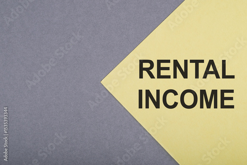 Close Up of Yellow Paper With Black Text Rental Income on Grey Background