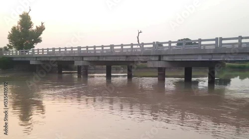 Beautiful 4K video of a bridge over a canal in Pakistan with water reflections, peaceful landscape, and scenic views of trees, cultural charm, and calm natural surroundings