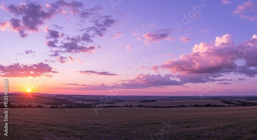 Fototapeta Naklejka Na Ścianę i Meble -  The sunset paints the sky in vibrant pink and purple over a tranquil landscape.