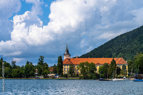 Beautiful view of St. Quirinus parish church on the lake side of Tegernsee lake in summer on a sunny day with blue sky cloud, Tegernsee, Bavaria, Germany