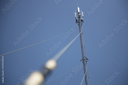 Tall Communication Tower Supporting High-Pressure Lines Against Clear Blue Sky