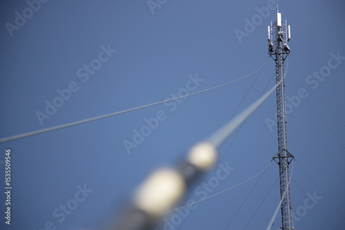 Tall Communication Tower Supporting High-Pressure Lines Against Clear Blue Sky