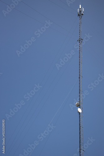 Tall Communication Tower with Satellite Dishes Against a Blue Sky