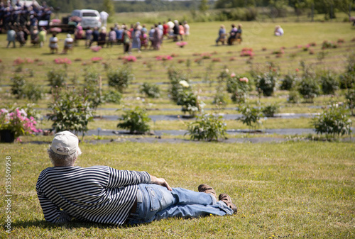 Man Relaxing on Grass Observing a Garden Gathering in Nature