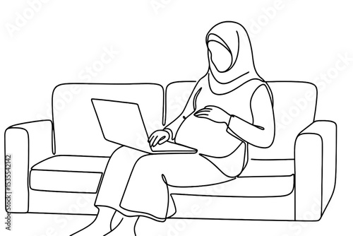 Pregnant woman working on laptop while seated comfortably on a couch at home during daytime