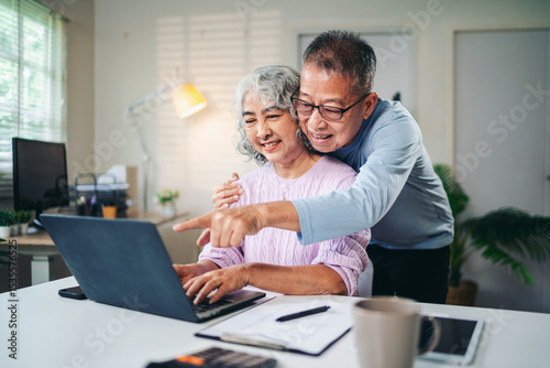 Senior Asian Couple Enjoying Retirement Planning Online Together at Home Using Laptop Computer Searching for Investment Ideas and Financial Security