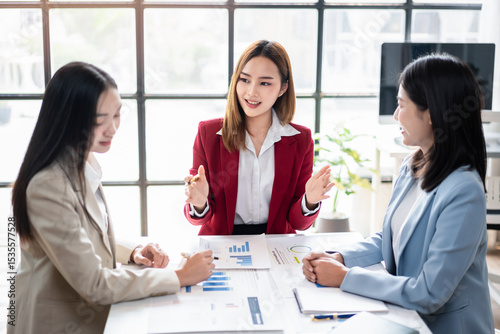 Three women are sitting at a table, discussing business matters