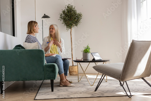 Senior therapist listening to young patient talking about mental health problems during therapy session