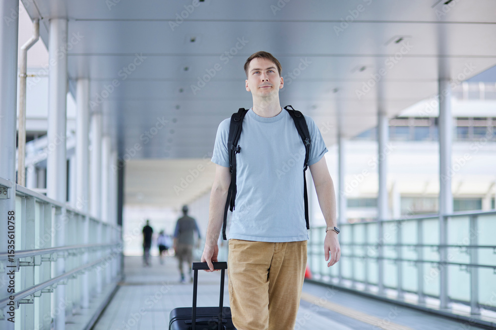 Fototapeta premium 駅の通路を笑顔で歩く男性旅行者