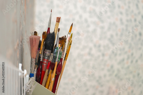 Assorted paintbrushes for artwork stored in a wall-mounted holder, showcasing an artist's creative tools