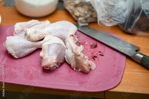 Chopped chicken drumsticks on a plastic cutting board with a knife nearby, ready for cooking preparation