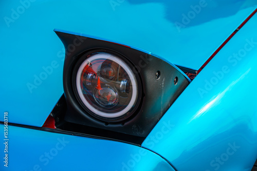 Pop up headlight of classic vehicle on display at car show.