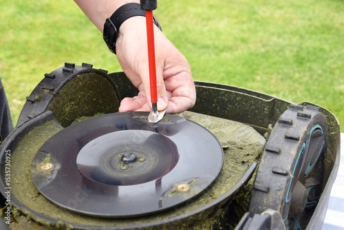 A man changes the blades of a robotic lawn mower.