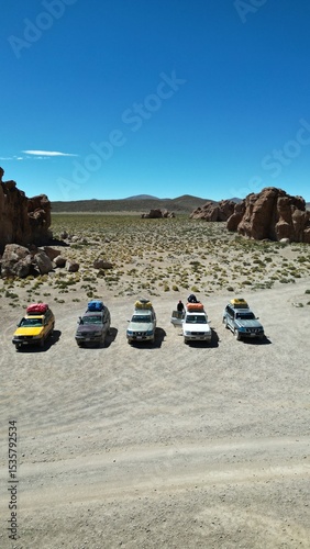 Convoy of 4x4 vehicles parked in Bolivia’s surreal Rock City desert landscape, surrounded by dramatic stone formations under a clear sky