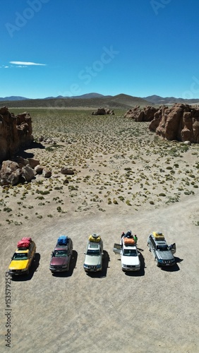Convoy of 4x4 vehicles parked in Bolivia’s surreal Rock City desert landscape, surrounded by dramatic stone formations under a clear sky