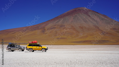 Colorful Bolivian lagoon surrounded by dramatic mountains, salt flats, flamingos, and off-road explorers in the remote altiplano