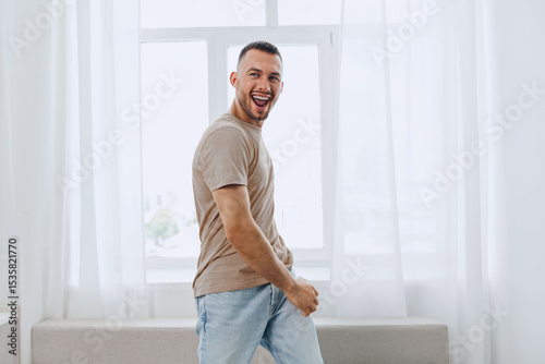 Happy man enjoying a moment of joy in a bright, modern interior, showcasing a trendy lifestyle that reflects the spirit of 2025's creative living trends. Free Download Happy man enjoying a moment of joy in a bright, modern interior, showcasing a trendy lifestyle that reflects the spirit of 2025's creative living trends. - GFXLoad