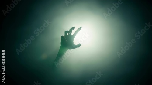 Green hand reaching up through smoke and mist. Horrifying zombie or alien arm. Dark and scary horror scene footage.