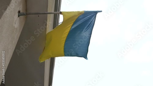 The blue and yellow flag of Ukraine hangs on the wall and flutters in the wind