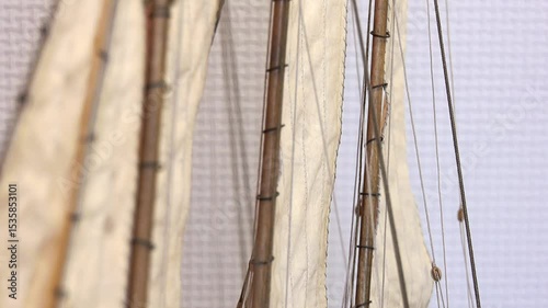 White sails on the masts of a handmade ship close up on a white background