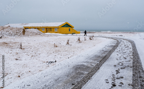 Frozen road with snow and an unrecognized man walking in winter in Iceland. Stormy weather