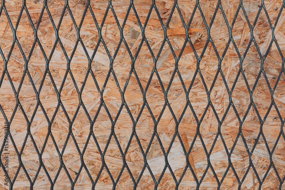 Naklejka premium Textured Wooden OSB Board Behind Metal Mesh Fence