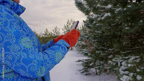 Female explorer navigating a snowy forest using a smartphone
