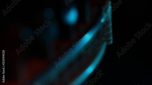A dramatic close-up rack focus reveals the wooden bridge and strings of a cello. Moody blue and orange light creates a cinematic atmosphere against a dark background.