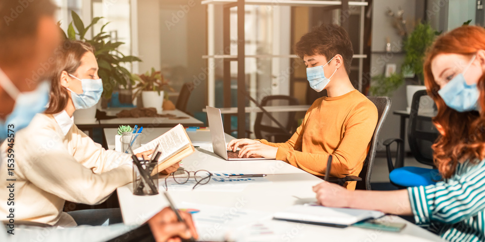 Fototapeta premium Prevention And Precautions. Group of diverse international students or employees wearing protective surgical masks using laptop computers, studying and working, people reading and writing in office