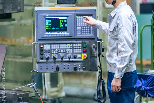 Obraz na płótnie 工場で操作盤で機械を操作する男性作業員