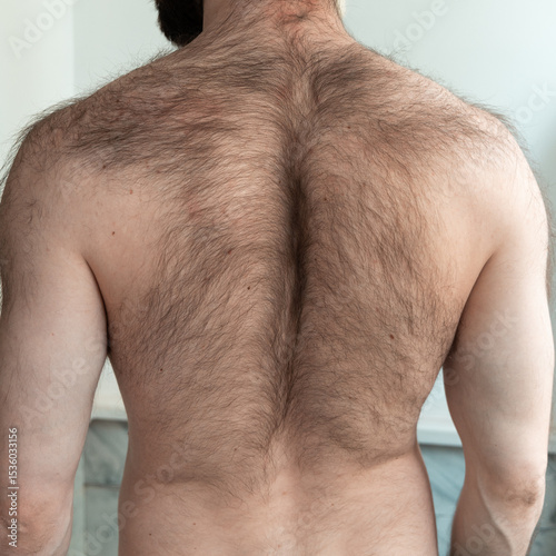 Bearded man seen from behind, showing unshaved neck and tied back hair.  masculinity, grooming or personal care