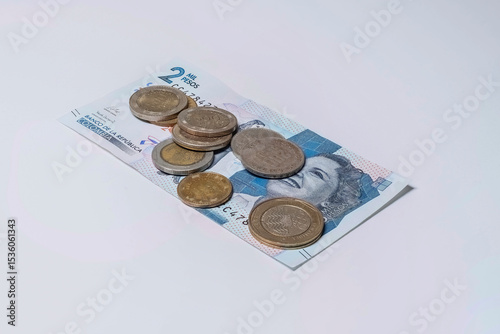 Close up of a colombian money bill and coins, on a white background. COP.