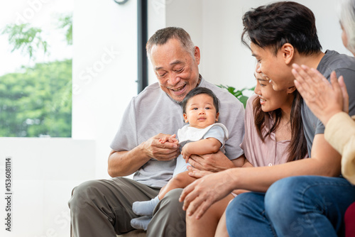 Portrait of Happy Asian Family at Home, Happy Grandparents, Parents, and Baby Bonding on Sofa, Multi-Generational Asian Family Smiling Together at Home