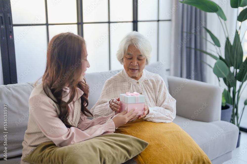 Obraz premium Young asian woman giving a gift to her Grandmother