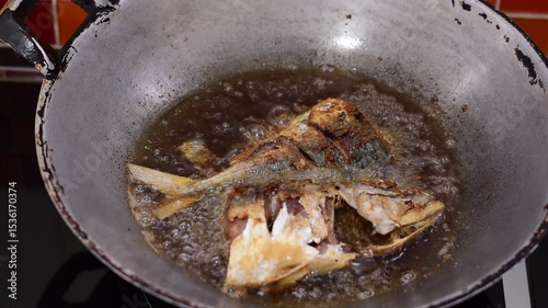 Old used cooking oil in dirty iron pan on a stove and space for write wording, fish fried in a frying pan, fish frying in oil on the fire, dangers of used cooking oil 
