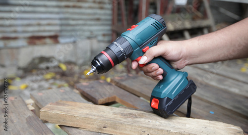 Impact Drill Machine : A close-up shot of a hand firmly gripping an electric drill a rough wooden backdrop.