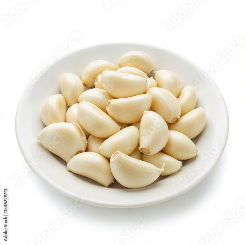 Fresh garlic cloves sit peeled on a white plate ready for cooking use