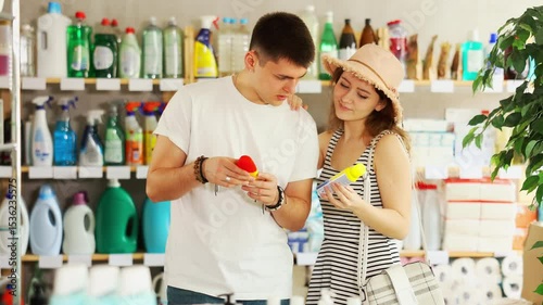 Young couple in summer clothes stands in a supermarket and chooses a protective repellent from insects and mosquitoes. Shoppers looking at sprays for hiking in the forest in the supermarket. High